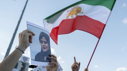 Un manifestant brandit une photo de Mahsa Amini sous l'ancien drapeau iranien, à Istambul (Turkey), en octobre 2022. (BULENT KILIC / AFP)