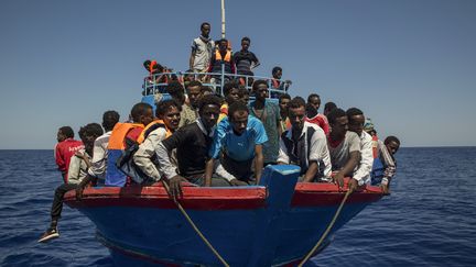 Des migrants attendent de monter à bord d'un navire des ONG SOS-Méditerranée et Médecins Sans Frontières, au large des côtes de la Libye, le 2 août 2017. (ANGELOS TZORTZINIS / AFP)