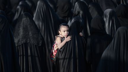 Une jeune Bahre&iuml;nienne est port&eacute;e par sa m&egrave;re lors de fun&eacute;railles &agrave;&nbsp;Karzakkan (Bahre&iuml;n), le 28 mai 2013. (MOHAMMED AL-SHAIKH / AFP)