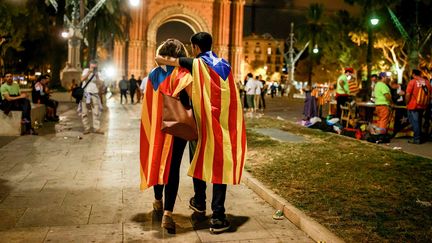 Deux personnes&nbsp;portent le drapeau indépendantiste catalan dans les rues de Barcelone, le 10 octobre 2017. (GONZALO ARROYO MORENO / ANADOLU AGENCY / AFP)