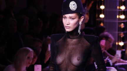 Alexandre Vauthier a recréé l'atmosphère d'une boîte de nuit, avec boules à facettes, miroirs et sièges en cuir. La musique résonne et ses séductrices avancent, sûres d'elles et sexy. Le mannequin star Bella Hadid ouvre le bal dans un haut noir transparent, une jupe culotte à taille haute et des bottes roses métallisées. Suivent des robes ultra-courtes, ou longues et fendues pour dévoiler les jambes, des tissus lamés, du cuir, pour un vestiaire d'oiseau de nuit chic. 
 (FRANCOIS GUILLOT / AFP)