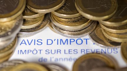 Avis d'imposition à peine caché par des pièces de monnaie. (JOEL SAGET / AFP)