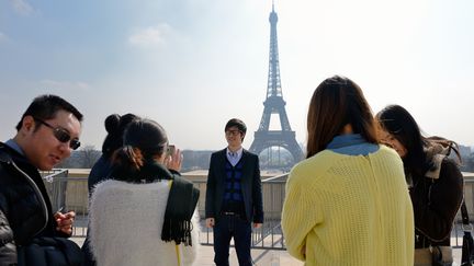 Un groupe de touristes chinois pose devant la tour Eiffel, le 27 mars &agrave; Paris.&nbsp; (ERIC FEFERBERG / AFP)