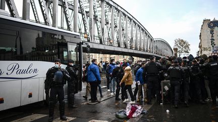 Des gendarmes encadrent l'évacuation de migrants sans-abri vers des centres d'hébergement d'urgence lors du démantèlement d'un camp à Paris, le 17 novembre 2022. (CHRISTOPHE ARCHAMBAULT / AFP)