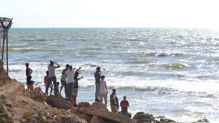 Des Libanais regardent vers la mer, près du poste-frontière d'Arida avec la Syrie, le 23 septembre 2022, alors que des proches attendent l'arrivée des corps des personnes qui se sont noyées lors du naufrage d'un bateau au large de la Syrie. (FATHI AL-MASRI / AFP)