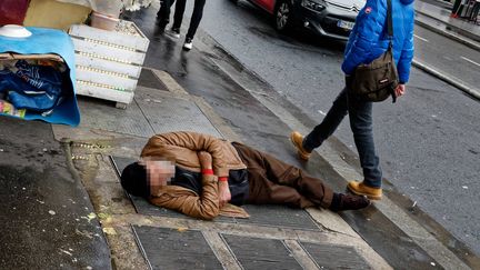 Un sans-abri allongé sur un trottoir rue Lafayette à Paris. (DANIEL FOURAY / MAXPPP)