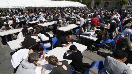 Tout le monde planche, sous le soleil, à la 20e édition de la "Dictée des cités" à Saint Denis le 30 mai 2015.
 (THOMAS SAMSON / AFP)