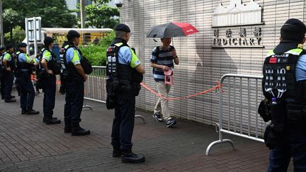 La police observe les personnes entrant dans le tribunal de West Kowloon (Hong Kong), le 5 juillet 2024, lors de la comparution d'activistes prodémocratie. (PETER PARKS / AFP)