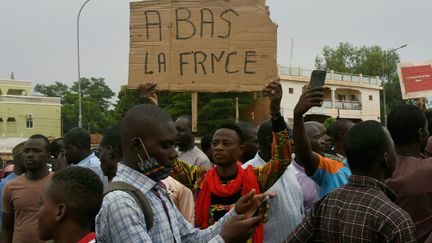 Un homme brandit une pancarte indiquant "A bas la France"&nbsp; lors d'une manifestation contre la présence militaire française au Niger, le 18 septembre 2022 à Niamey. (BOUREIMA HAMA / AFP)