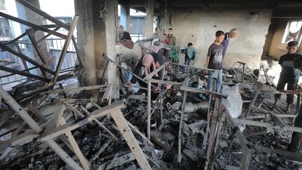 Des résidents inspectent les dégâts après les attaques israéliennes sur une école, dans le camp de réfugiés de Nuseirat, dans le centre de la bande Gaza, le 14 octobre 2024. (HASSAN JEDI / ANADOLU / AFP)