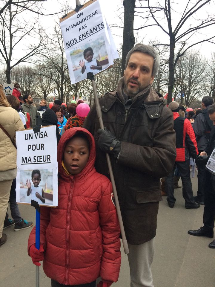 Nicolas Lejeune&nbsp;manifestent à Paris avec son fils Luxon, le 19 décembre 2016. Il réclame un visa pour permettre à sa fille adoptive d'entrer en France. (MARIE-VIOLETTE BERNARD / FRANCEINFO)