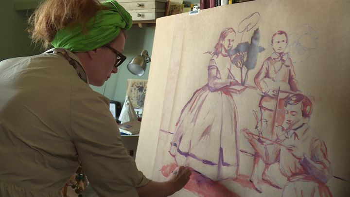 Nathalie Novi, l'iniatrice du projet de fresque collective, en train de peindre sa "famille confinée",&nbsp;dans son atelier du Jura. (H. Perret / France Télévisions)