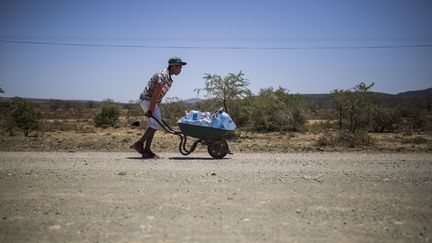 Un jeune&nbsp;homme pousse une brouette&nbsp;avec des bouteilles d'eau sur une route menant au township de Bezuidenhoutville près d'Adelaïde, dans l'est de l'Afrique du Sud. Photo prise le 28 novembre 2019. (GUILLEM SARTORIO / AFP)