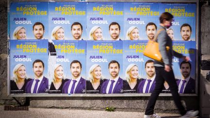 Une personne passe devant des affiches de Julien Odoul, candidat du Rassemblement national aux élections régionales de Bourgogne-Franche-Comté, le 4 avril 2021 à Montbéliard. (LIONEL VADAM  / MAXPPP)