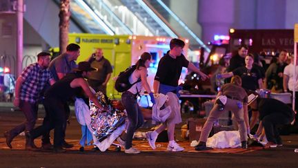 Une personne blessée par la fusillade à Las Vegas (Nevada, Etats-Unis) est transportée par d'autres, le 2 octobre 2017. (ETHAN MILLER / GETTY IMAGES NORTH AMERICA)