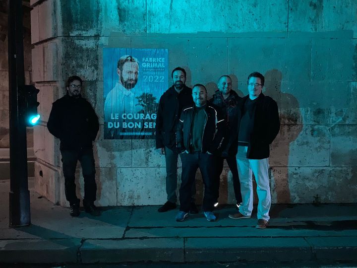 Fabrice Grimal, candidat à l'élection présidentielle de 2022 (à droite de l'affiche), et des militants après avoir collé des affiches dans Paris, janvier 2022. (VICTORIA KOUSSA / RADIO FRANCE)