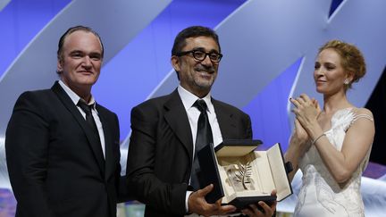 Toujours en 2014, Quentin Tarantino remet la Palme d'or au cinéaste turque&nbsp;Nuri Bilge Ceylan pour son film Winter Sleep. Pour cette cérmonie de clôture du 67e festival de Cannes, il est accompagné de l'actrice Uma Thurman. (VALERY HACHE / AFP)