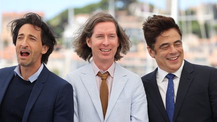 Le réalisateur Wes Anderson célèbre son film "The French Dispatch", un succès lors de sa projection cannoise. Il est entouré de ses acteurs Adrien Brody à gauche et Benicio Del Toro à droite (VALERY HACHE / AFP)