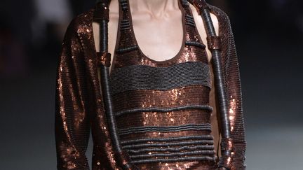 Chez Givenchy, Riccardo Tisci a imaginé des femmes-bijoux: certains mannequins ont le visage dissimulé sous du maquillage comme un masque de pierres précieuses colorées. Elles sont superbes dans des drapés noirs qui laissent voir une partie du corps. Le ventre s'exhibe quand le décolleté est couvert. Il y a beaucoup de brillance. Un pantalon en sequins couleur bronze est porté avec un haut noir drapé: un air des années 70. Des looks donnent l'impression d'avoir été déconstruits pour être reconstruits. Le show se termine avec des robes très couture avec de beaux décolletés et dos nus.
 (MIGUEL MEDINA / AFP)