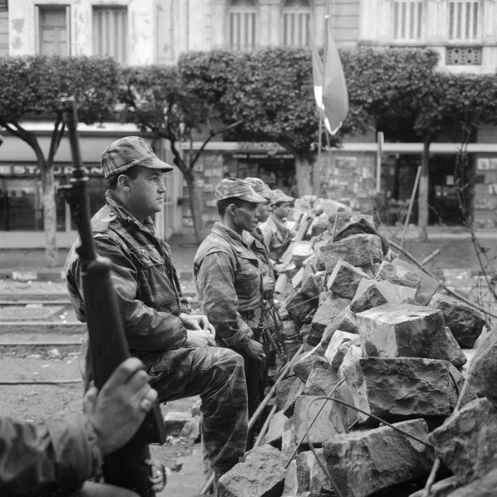 Des parachutistes, qui ont fraternisé avec les insurgés, sont alignés&nbsp;le 31 janvier 1960 devant les barricades dressées&nbsp;à Alger pendant la "emaine des barricades". (JEAN-CLAUDE COMBRISSON / AFP)