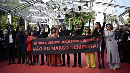 Le Festival de Cannes est aussi une grande tribune politique. Le temps de quelques instants, la Croisette a été le théâtre d'une manifestation de l'équipe du film "Crowra", de Joao Salaviza. Ils dénoncent le "cadre temporaire" au Brésil, une mesure qui oblige les peuples autochtones à prouver qu'ils vivaient déjà sur le territoire avant l'entrée en vigueur de la Constitution brésilienne pour en revendiquer la propriété. (LOIC VENANCE / AFP)