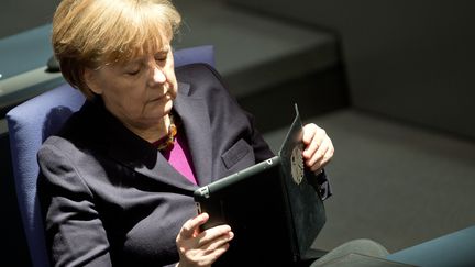 La chanceli&egrave;re allemande Angela Merkel lit sa tablette num&eacute;rique, le 20 mars 2014, au Bundestag de Berlin (Allemagne). (BERND VON JUTRCZENKA / DPA)