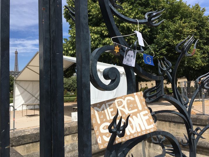 Une pancarte et un cintre rendant hommage à Simone Veil sont accrochés aux grilles de l'entrée des Invalides, le 5 juillet 2017, jour des obsèques de cette figure de la politique française.&nbsp; (JULIE RASPLUS / FRANCEINFO)