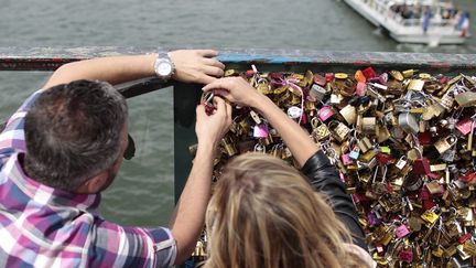 Un couple accroche un cadenas d'amour sur le Pont des Arts à Paris. Un geste impossible à partir du 1er juin 2015.
 (Charly Triballeau / AFP)