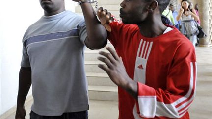 Theophile Kouamouo (g), et Saint Claver Oula arrivent au palais de Justice d'Adibjan, le 19 juillet. (AFP - Sia Kambou)