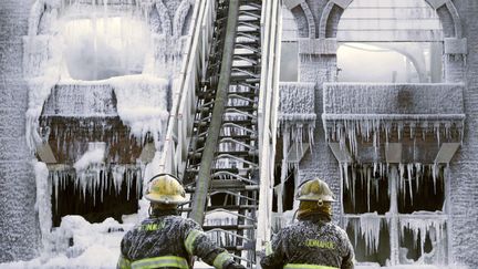 Des pompiers contemplent un&nbsp;b&acirc;timent recouvert de glace apr&egrave;s avoir &eacute;teint l'incendie qui le ravageait &agrave;&nbsp;Philadelphie (Pennsylvanie), le 16 f&eacute;vrier 2015. (JACQUELINE LARMA / AP / SIPA  )