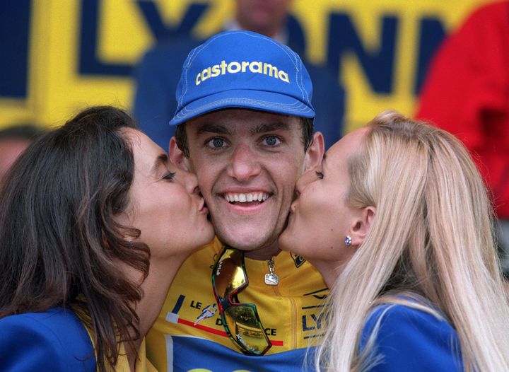 Jacky Durand, maillot jaune surprise du Tour 1995, est embrassé par les hôtesses sur le podium du prologue de Saint-Brieuc (Côtes d'Armor), le 2 juillet. (PASCAL PAVANI / AFP)