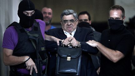 Le leader du parti n&eacute;onazi grec Aube dor&eacute;e, Nikos Michaloliakos, est escort&eacute; &agrave; sa sortie du poste de police &agrave; Ath&egrave;nes (Gr&egrave;ce), le 28 septembre 2013. (ANGELOS TZORTZINIS / AFP)