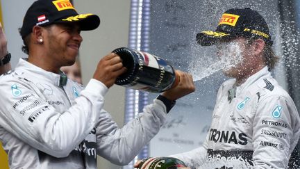 Le pilote anglais Lewis Hamilton asperge de champagne son co&eacute;quipier, allemand Nico Rosberg, le 22 juin 2014, sur le podium du Grand Prix d'Autriche. (HOCH ZWEI / AFP)