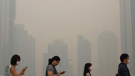 Des citoyens de Singapour portent des masques dans le quartier d'affaires en raison de la pollution liée au nuage de fumée qui s'est abattu sur la cité-Etat (21-6-2013). (Reuters - Edgar Su)