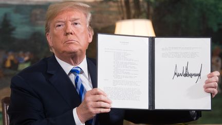 Donald Trump avec le document rétablissant les sanctions contre l'Iran après avoir annoncé le retrait américain de l'accord nucléaire iranien, le 8 mai 2018. (SAUL LOEB / AFP)