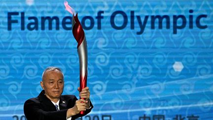 La flamme olympique brandie par le secrétaire du Parti communiste chinois Cai Qi, le 20 octobre 2021. (NOEL CELIS / AFP)