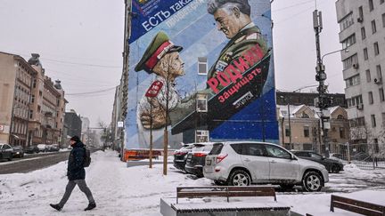 Un piéton à Moscou passe devant une peinture murale représentant un général russe et un cadet avec le slogan : "Défendre la patrie", le 17 janvier 2023. Photo d'illustration. (YURI KADOBNOV / AFP)