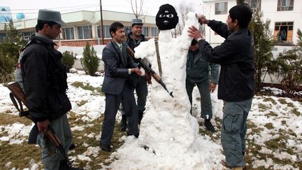 Des policiers afghans font un bonhomme de neige devant le commissariat de Baghlan (Afghanistan), le 12 mars 2012. (NAQEEB AHMED / EPA / MAXPPP)