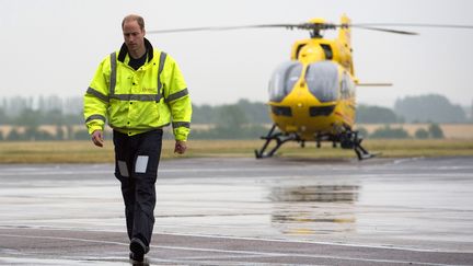 Le Prince William et un&nbsp;hélicoptère-ambulance de la compagnie&nbsp;East Anglian Air Ambulance, pour laquelle il est pilote, le 13 juillet 2015 à l'aéroport de Cambridge. (REUTERS)