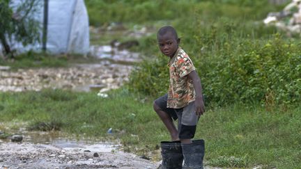 Un jeune gar&ccedil;on porte des bottes trop grandes apr&egrave;s le passage de l'ouragan Sandy &agrave; Port-au-Prince (Ha&iuml;ti), le 25 octobre 2012. (SWOAN PARKER / REUTERS)