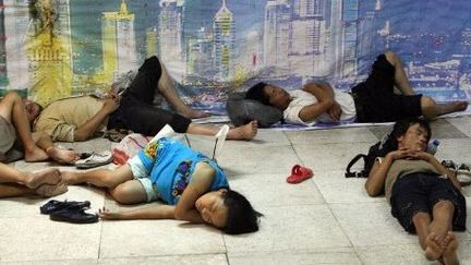 Des mingong s'abritant près d'une bouche d'air conditionné dans le métro, à Shanghai, en 2007. (AFP/MARK RALSTON)