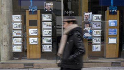 Un homme passe devant une agence immobili&egrave;re, le 18 mars 2013, &agrave; Paris. (FRED DUFOUR / AFP)