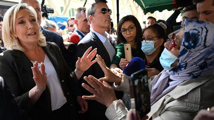 Marine Le Pen parle avec une femme lors d'une visite de campagne sur le marché de Pertuis, dans le sud de la France, le 15 avril 2022. (CHRISTOPHE SIMON / AFP)