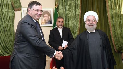 Le PDG de Total, Patrick Pouyanné, serre la main du président iranien Hassan Rohani, le 28 janvier 2016 à Paris. (ERIC FEFERBERG / AFP)