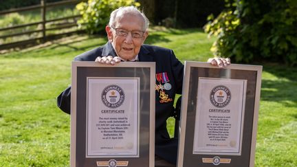 Le vétéran britannique Tom Moore pose avec les certificats de ses deux records homologués par le Guinness, le 24 avril 2020 à Marston Moreteyne (Royaume-Uni). (EMMA SOHL / GUINNESS WORLD RECORDS)