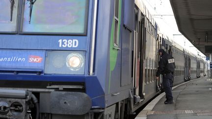 Un policier s'apprête à monter à bord d'un Transilien en région francilienne. (MIGUEL MEDINA / AFP)