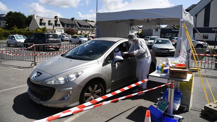 Un biologiste procède à un dépistage de Covid-19 sur un parking de Plabennec (Finistère), le 20 juillet 2020. (FRED TANNEAU / AFP)