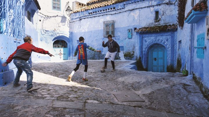 Enfants jouant au football dans les rues de Chefchaouen (nord du Maroc). Photo présentée dans l'exposition "Foot et monde arabe" à l'Institut du monde arabe à Paris. (Joseph Ouechen)