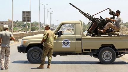 Des forces de sécurité libyennes montent la garde à un poste de contrôle, le 23 août 2018, sur le site d'une attaque dans la ville de Zliten, à 170 km à l'est de la capitale Tripoli. Cette attaque avait tué six soldats du gouvernement Sarraj soutenu par l'ONU. (MAHMUD TURKIA/AFP)