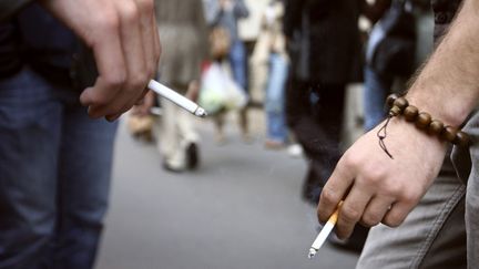 Des personnes fument sur un trottoir de Paris, le 16 octobre 2006. Le tabac est la cause de nombreux cancers évitables. (THOMAS COEX / AFP)